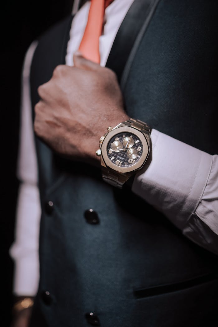 Close-up of a stylish man wearing a blue jacket and luxury watch, embodying elegance and sophistication.