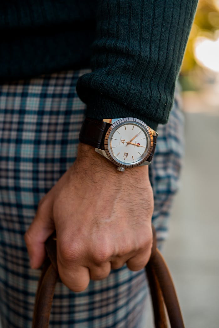 Close-up of a man's hand wearing a luxury wristwatch with stylish clothing and accessory.